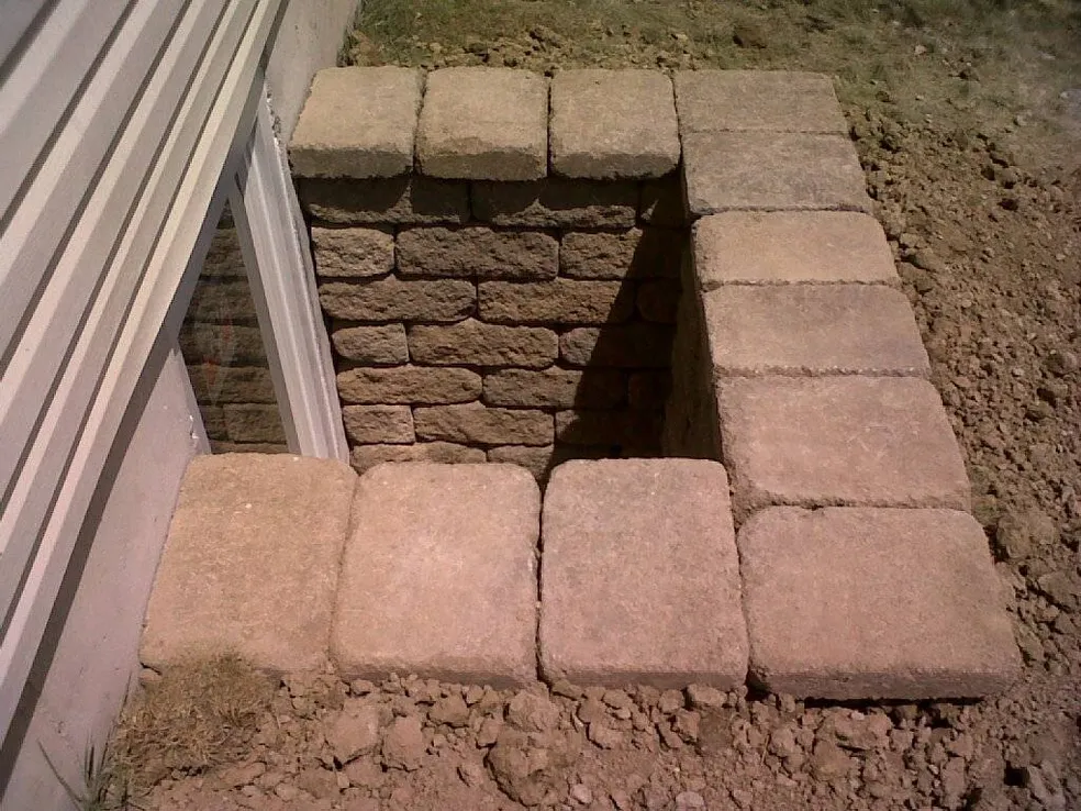 Flat capstones on top course of custom stone egress window well