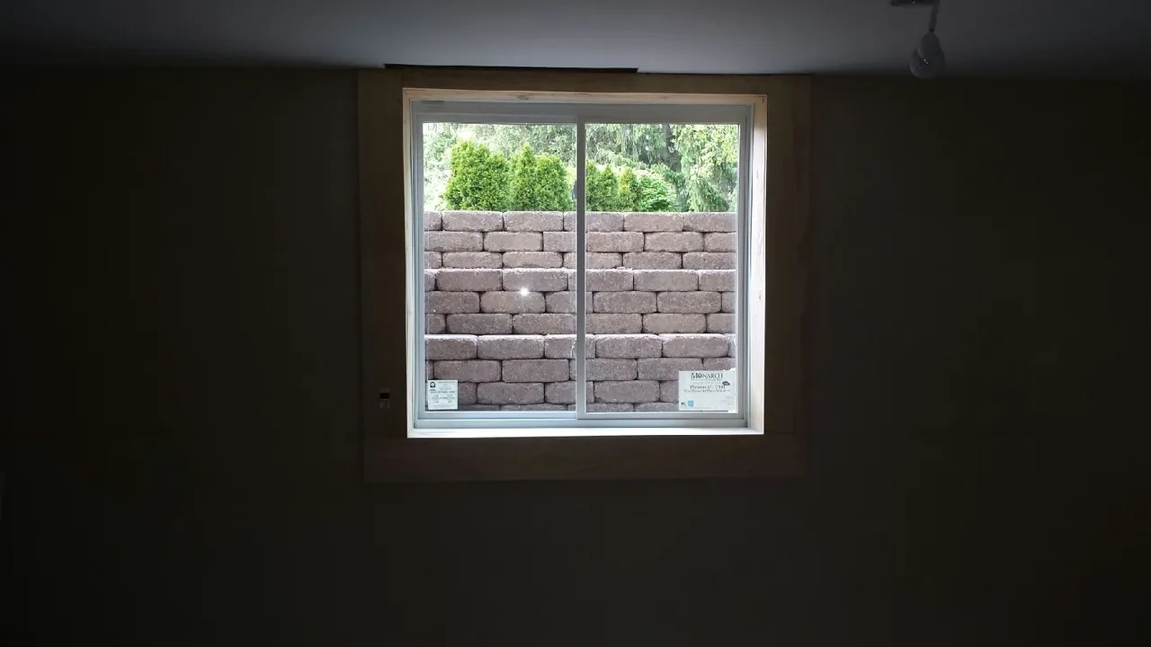 Custom retaining wall stone window well, horizontal slider egress window